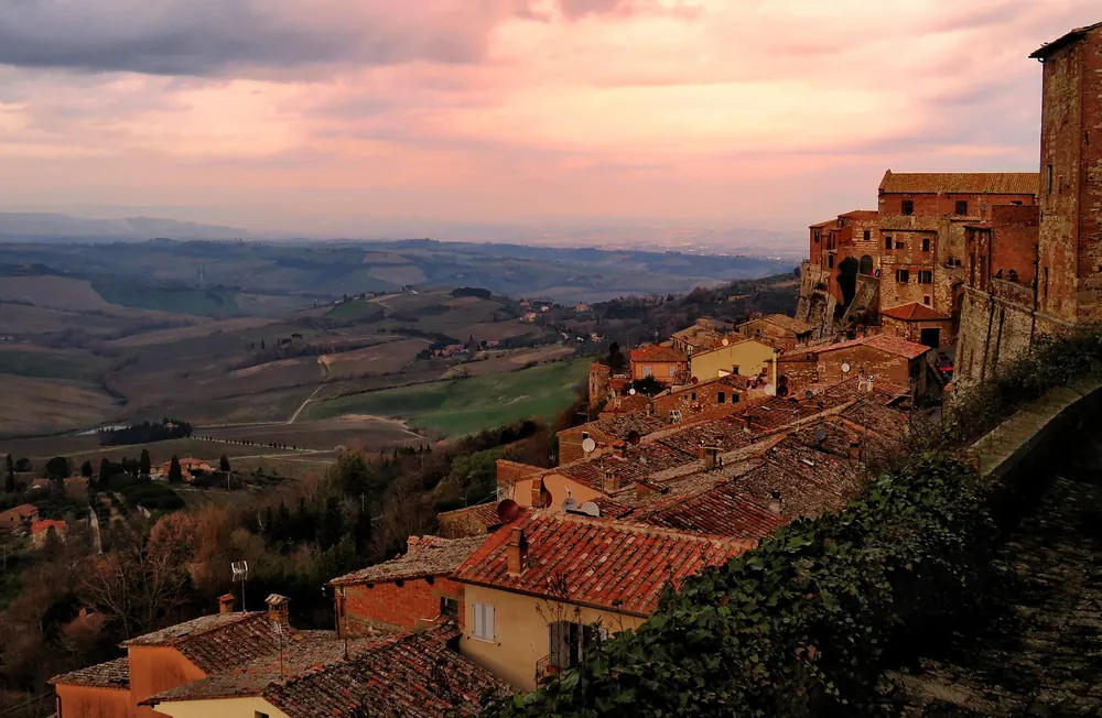 The hill town of Montepulciano at sunset, its rooftops falling away to the Tuscan valley below